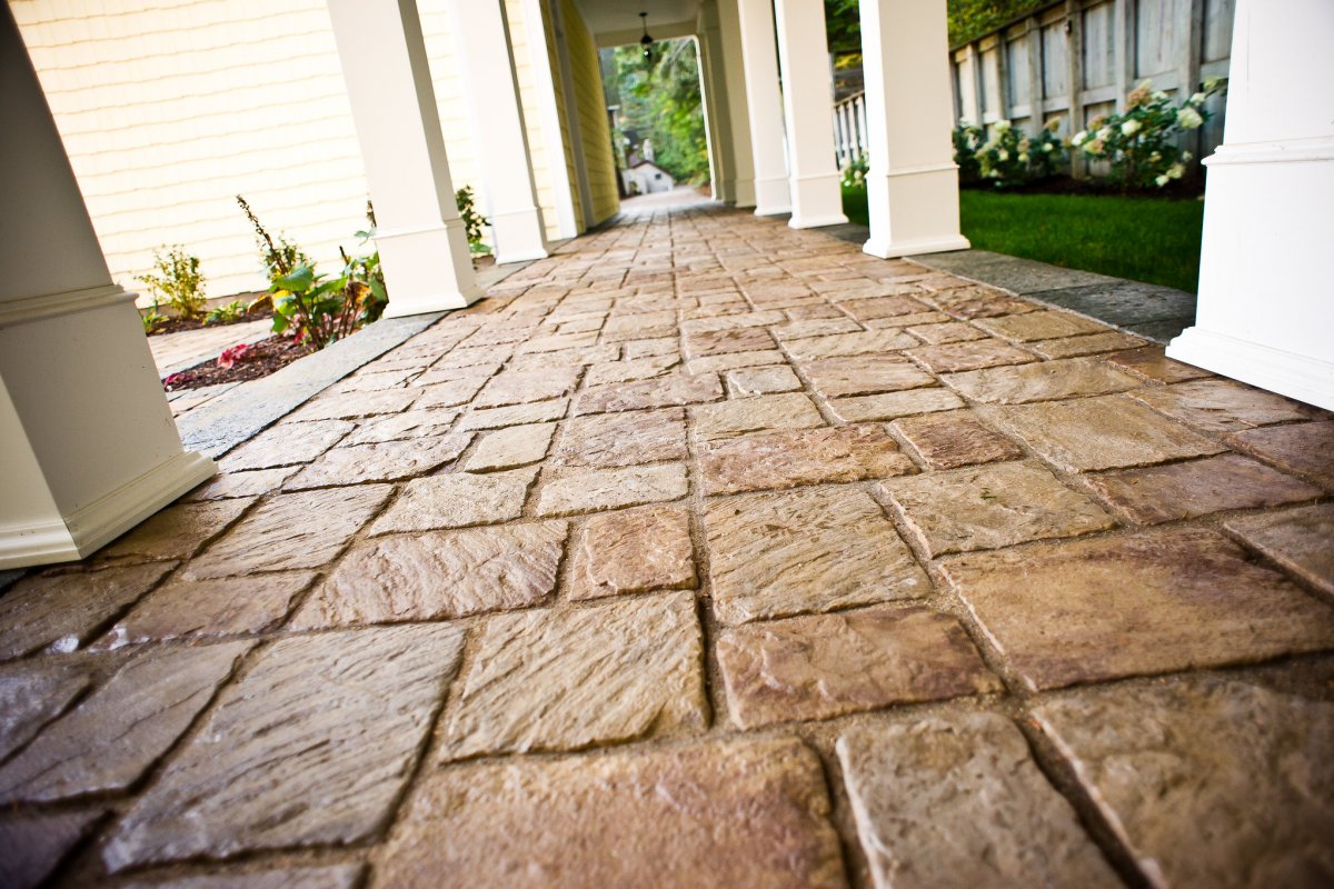 Weathered residential paver patio in Greater Binghamton NY showing sunken sections and weed growth in joints after winter freeze-thaw damage in need of professional restoration