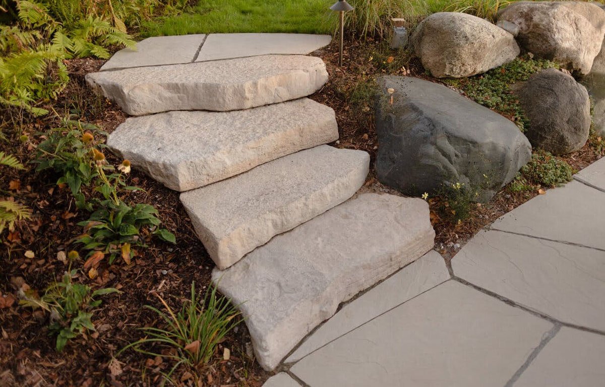 Professional stone walkway leading to a home entrance with landscape lighting in Binghamton NY